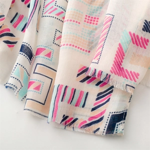 Macro detail of geometric print scarf showing linen texture and soft fringe edges