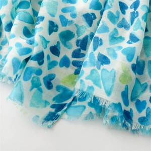 Détail macro du foulard à imprimé cœurs bleus avec bords effilochés et toucher lin doux