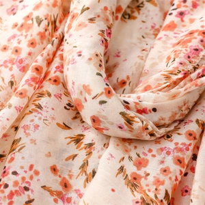 Gros plan sur la texture coton-lin avec de doux motifs floraux orange sur tissu léger
