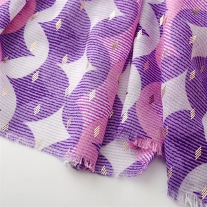 Macro detail of geometric print scarf with gold metallic stripes and frayed edges