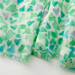 Détail d'une écharpe blanche légère avec motif de cœurs aquarelle verts et violets