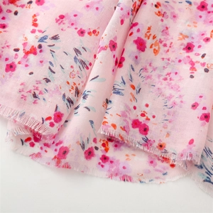 Gros plan d'un tissu floral rose léger avec des bords effilochés pour écharpes