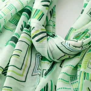 Detail of light green cotton linen scarf with geometric stripes and leaf patterns