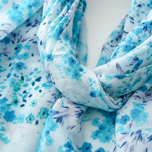 Gros plan sur le motif floral doux et la texture semi-transparente du foulard bleu fin