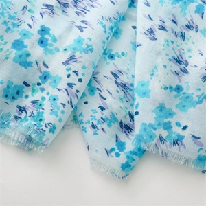 Détail de l'écharpe bleu clair en coton-lin avec imprimé floral violet et bords effilochés