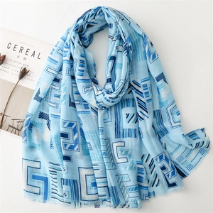 Detail of light blue geometric cotton linen scarf with fine frayed edges on a white desk