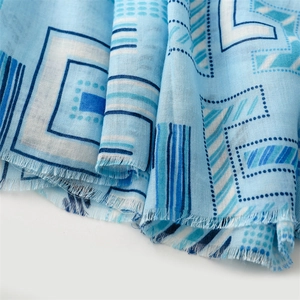 Detail of blue geometric cotton-linen scarf showing soft texture and fringed edges