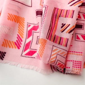 Detail showing pink linen-feel scarf with colorful geometric patterns and frayed edges