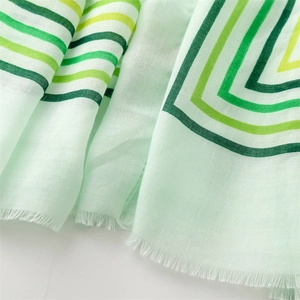 Detail of light green cotton linen scarf showing soft texture and raw frayed edges