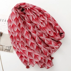 Detail of red and white leaf pattern scarf with fine tassel fringe on white background