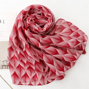 Detail of red and white leaf pattern printed scarf with delicate fringe edges and soft texture