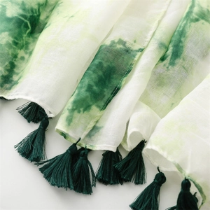 Texture détaillée de l'écharpe en viscose tie-dye blanc et vert avec des glands vert foncé