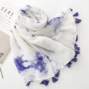 Détails d'une écharpe à dégradé d'encre blanc et violet avec des pompons faits à la main