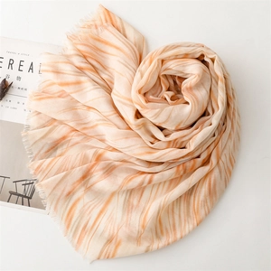Detail of soft linen scarf featuring orange marble patterns and delicate fringe edges