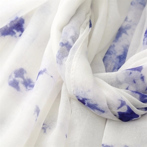 Détail du motif à l'encre dégradé bleu sur le tissu blanc léger du châle en fil de Bali