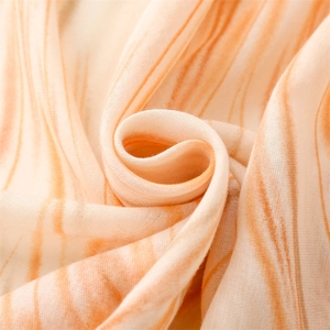 Close-up of soft cotton-linen scarf with orange and cream geometric wave patterns