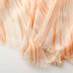 Detail of warm orange marble pattern lightweight scarf with natural raw frayed edges