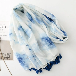 Détail d'une écharpe tie-dye bleue avec franges sur fond blanc avec magazine Cereal