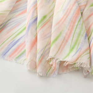 Detail of colorful striped scarf with raw fringe edges and soft lightweight fabric texture