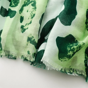 Macro shot of green leopard print cotton-linen scarf fabric with delicate frayed edges