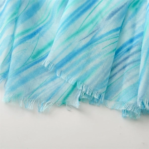 Macro view of blue and green marble pattern scarf with soft fringe edge details