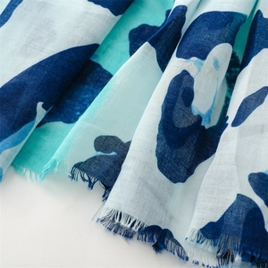 Close-up of blue and white abstract print scarf with natural frayed edges and linen texture