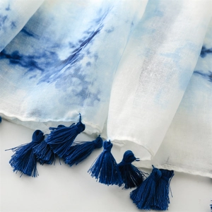 Gros plan d'une écharpe à dégradé bleu ciel avec de délicats pompons bleu foncé