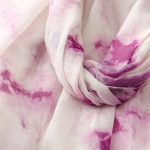 Détail macro d'une écharpe tie-dye magenta avec une texture respirante en coton et lin