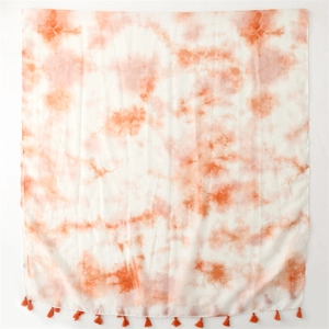 Détail d'une écharpe tie-dye orange montrant la texture du coton et les franges