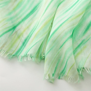 Detail of light green and beige striped scarf showing soft cotton-linen texture and frayed edges