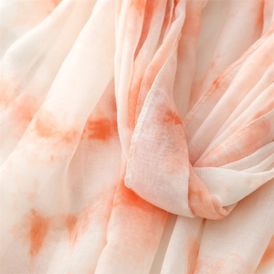 Gros plan d'une écharpe légère tie-dye orange et blanc montrant la texture fine