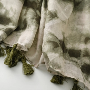 Nahaufnahme von grünem Batik-Pashmina-Stoff mit dekorativen Fransenquasten