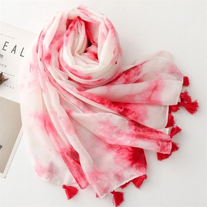 Vue détaillée du motif tie-dye rouge sur l'écharpe blanche avec détails de franges