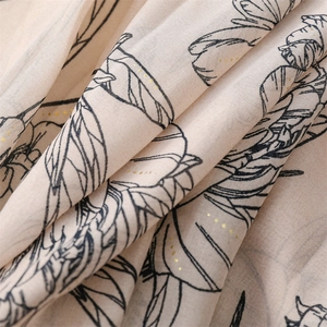 Vue macro d'une écharpe florale beige avec pois dorés et motifs imprimés
