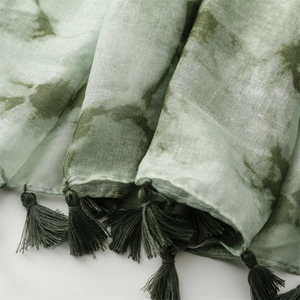 Detail eines grün-weißen Batikschals mit feinen Fransen und gewebter Textur