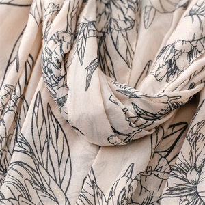 Détail macro de motif floral chinois avec feuilles d'or sur foulard en soie beige
