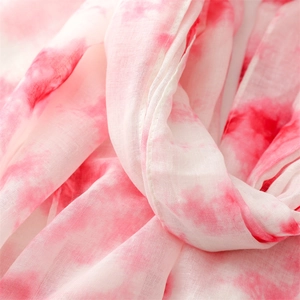 Gros plan d'une écharpe tie-dye rose et blanc montrant la texture tissée légère