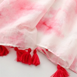 Détail du tissu tie-dye respirant avec des glands rouges éclatants sur la bordure
