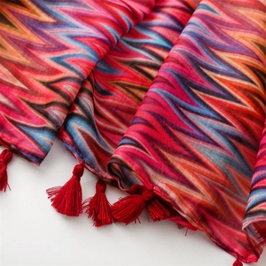 Detail of bohemian scarf with colorful zigzag patterns and red tassel fringe