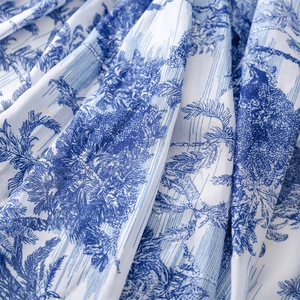 Close-up of blue tropical forest print fabric with subtle gold glitter details