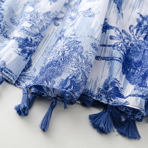 Detailed close-up of blue tassel fringe and floral pattern on a traditional shawl