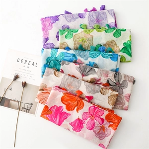 Detail shot of lightweight floral scarves with fringe tassels and soft cotton-linen texture