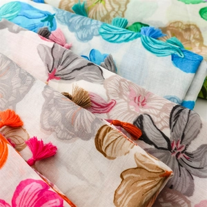 Detail of floral print scarves with cotton-linen texture and colorful handmade tassels