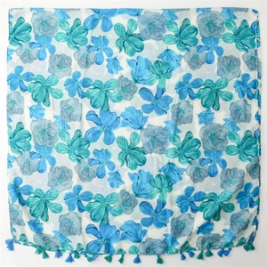 Detailed view of floral print linen scarf with blue and green tassel fringe trim