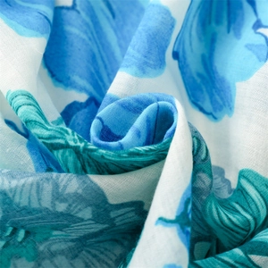 Detail of floral printed cotton linen scarf with soft folds and vibrant teal blue patterns