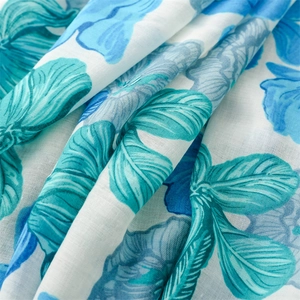 Detailed macro view of cotton-linen scarf fabric with blue floral patterns and green leaves