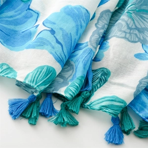 Close-up of blue floral print scarf fabric featuring detailed two-tone tassel fringes