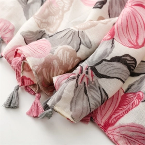 Detail of floral linen-feel scarf showing pink and grey patterns with tassel edges
