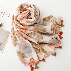 Detail of floral printed scarf featuring warm orange and brown tones with delicate tassels