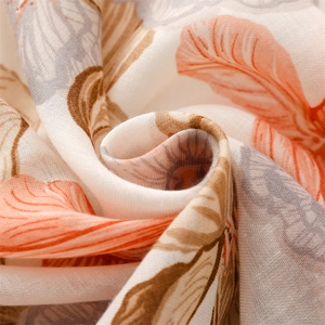 Close-up of cotton linen scarf showing orange floral prints and breathable fabric texture